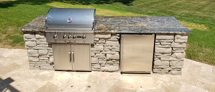 outdoor kitchen that includes a built in grill and refrigerator.