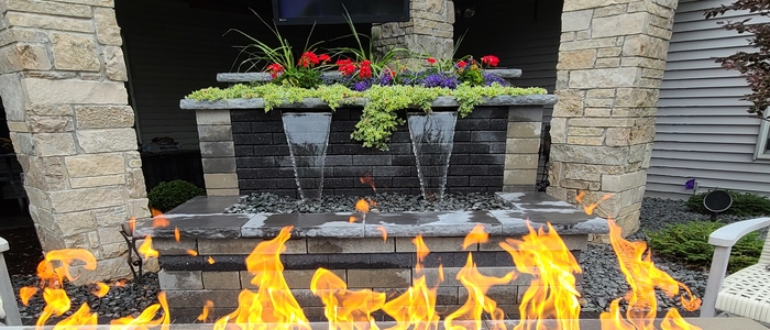 Water feature with flowers with a fire feature in the foreground.