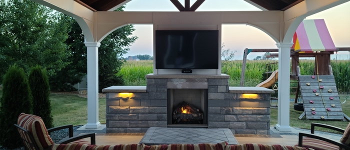 Outdoor entertaining at its finest, with fireplace and mounted TV, by Outdoor Innovations.