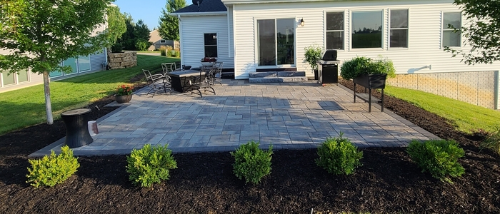 Patio by Outdoor Innovations featuring stone pavers, landscaping bushese and tress, with plenty of space for at home outdoor activities.