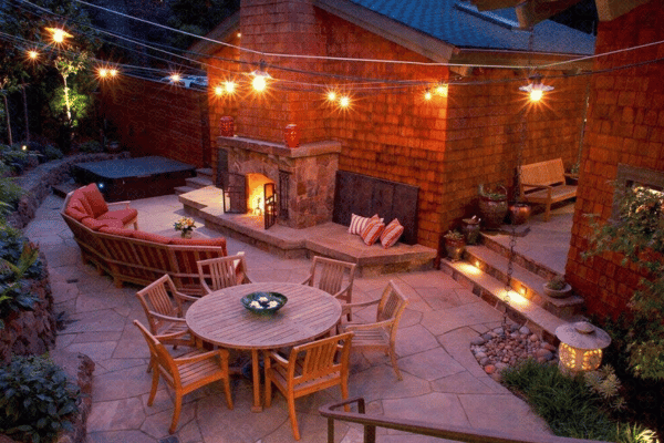 Overhead landscape lighting softly illuminating a patio and fireplace.